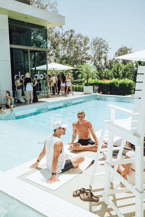 A photo of a group sitting on yoga mats around a pool at Alo Summer House 2022.
